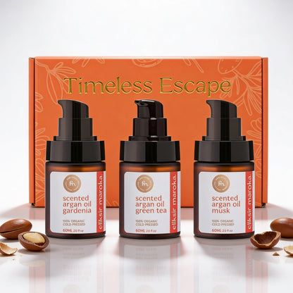 Zestaw prezentowy Timeless Escape od EliksirMaroka. Trzy organiczne, perfumowane olejki arganowe tłoczone na zimno – gardenia, zielona herbata i piżmo – wyeksponowane na tle eleganckiego pomarańczowego pudełka i autentycznych orzechów arganowych. | Timeless Escape gift set by EliksirMaroka. Three organic, cold-pressed scented argan oils – gardenia, green tea, and musk – displayed against an elegant orange box and authentic argan nuts.
